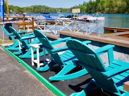 Teal Adirondack rockers lined up on the dock at Lake Hickory Pub and Marina, boats and the lake behind