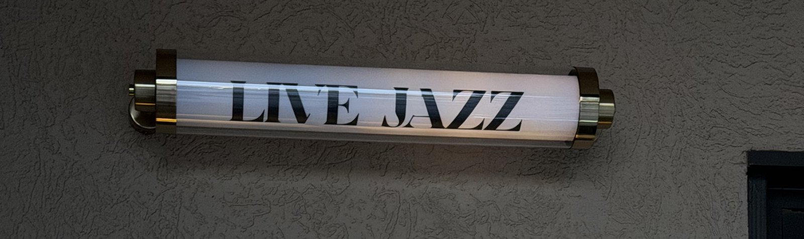 A glowing LIVE JAZZ light fixture on the wall outside The Downbeat in downtown Hickory, NC