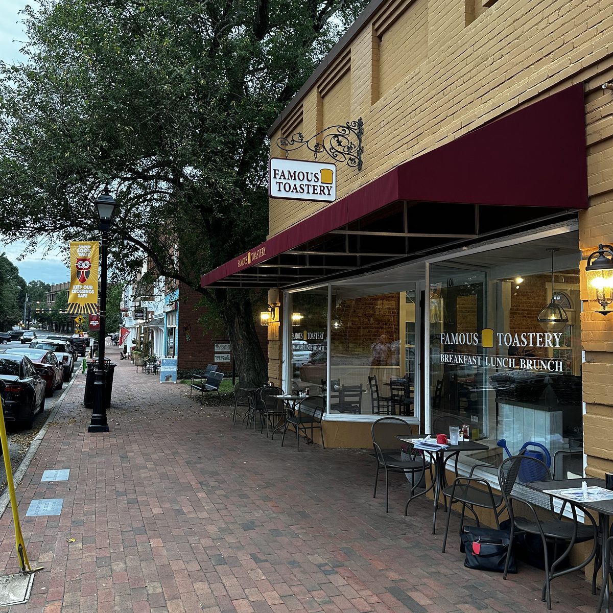 A Famous Toastery storefront on a brick sidewalk with sidewalk tables